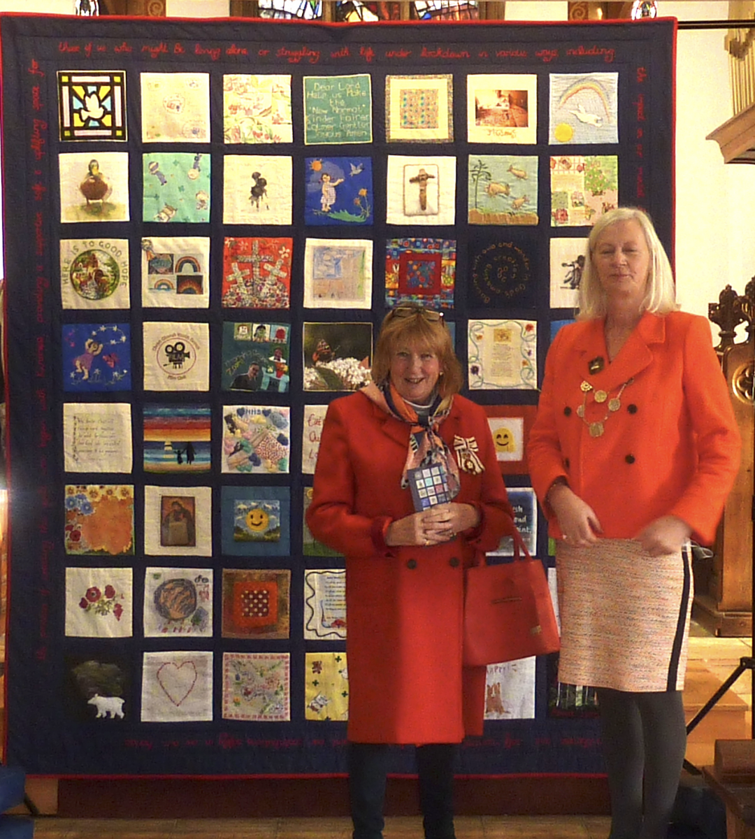 Lady Dannatt, Lord-Lieutenant of Norfolk, and Caroline Jarrold, Sheriff of Norwich, standing in front of a textile quilt in a Church