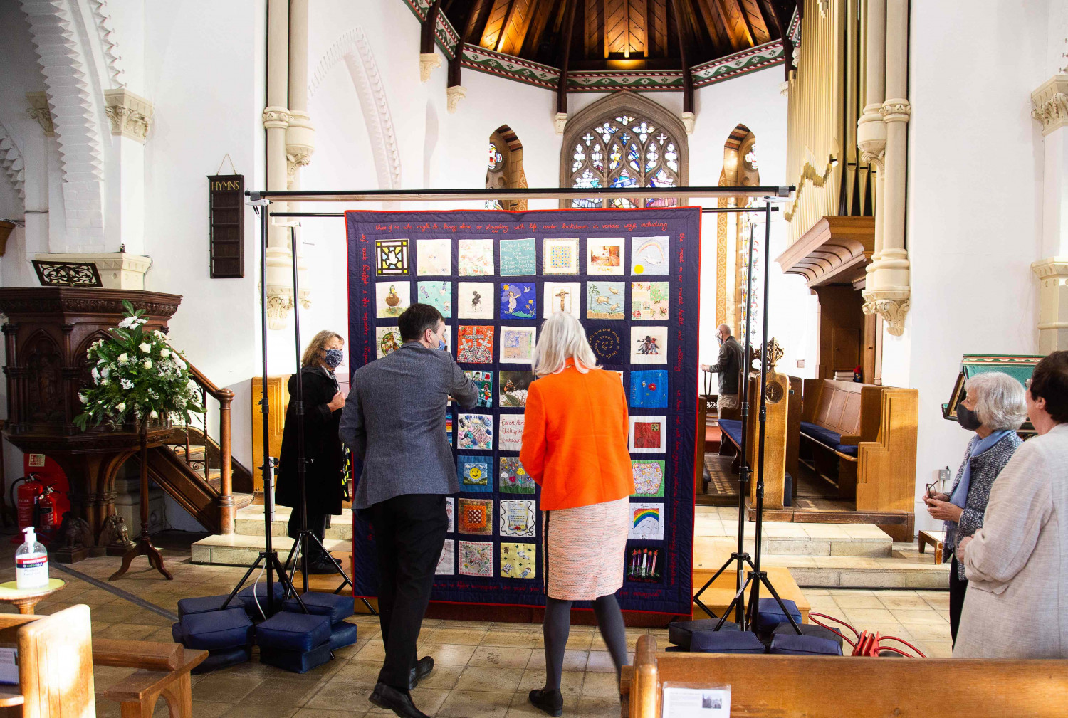 People looking at a textile quilt in a church