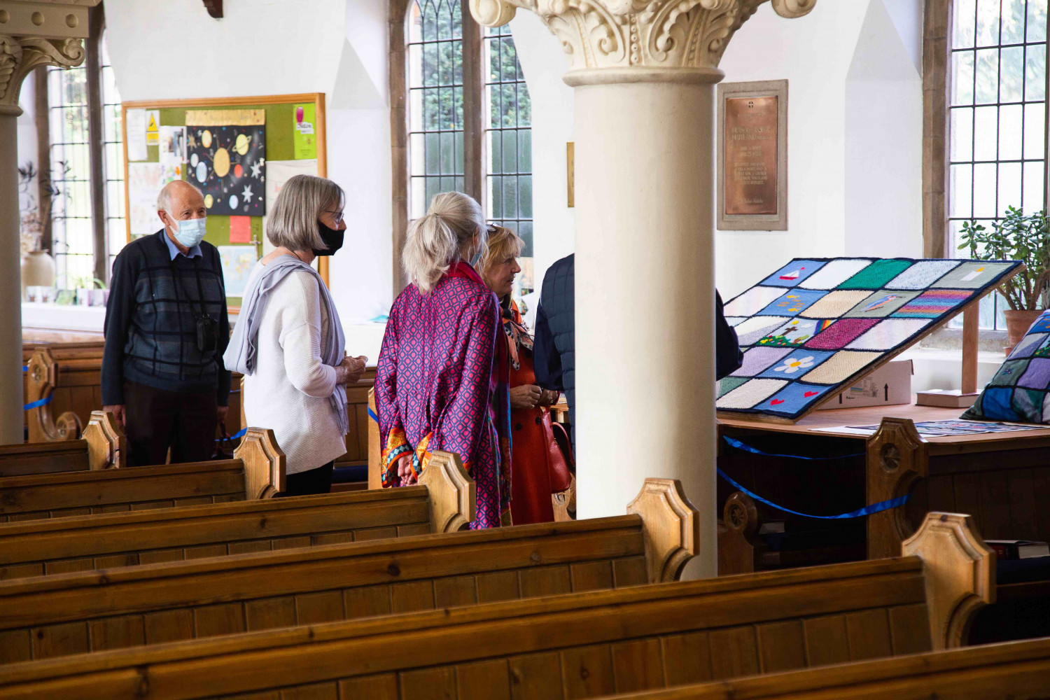 People looking at a knitted quilt in a church